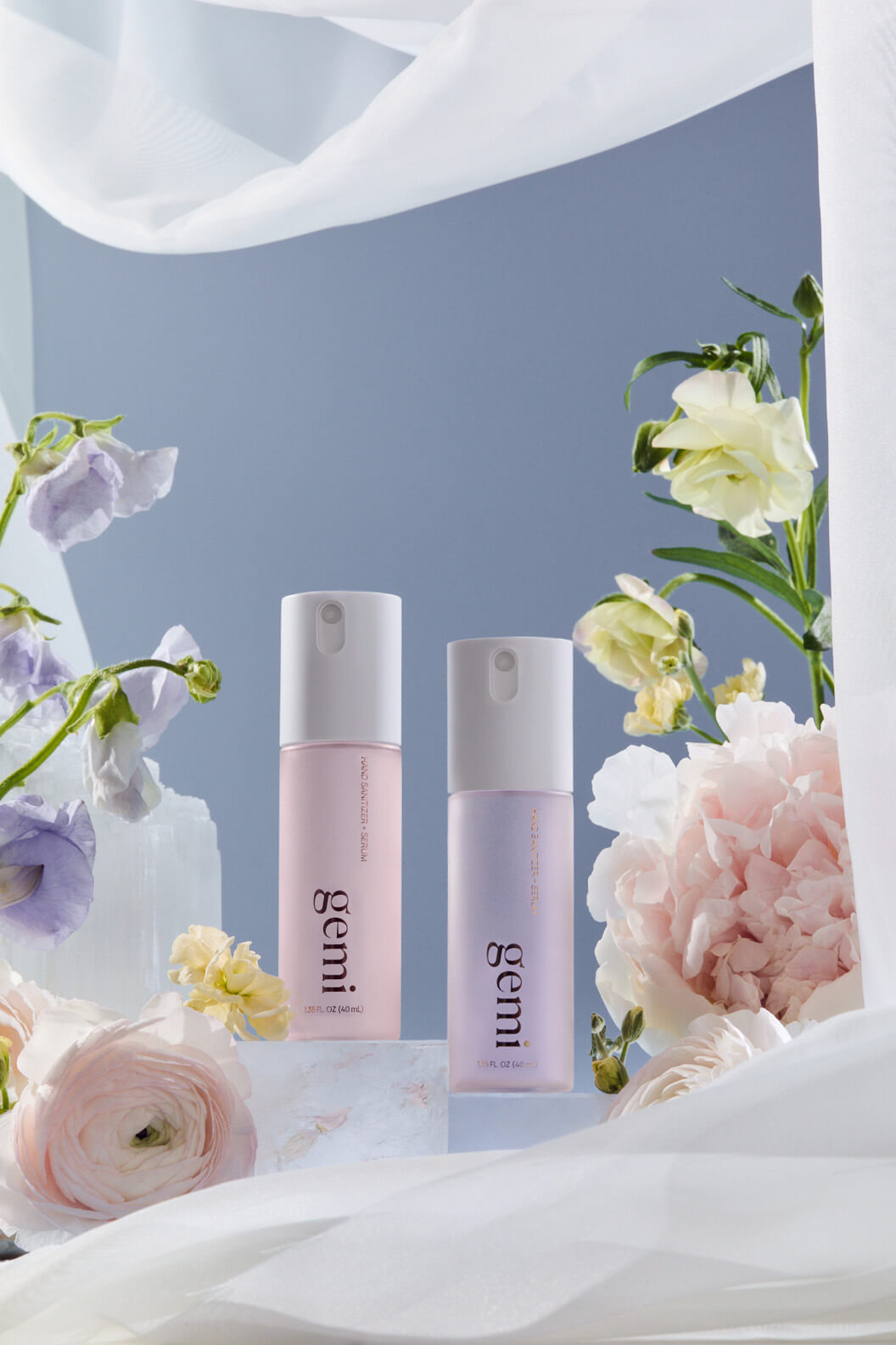 Two hand sanitizer bottles labeled 'gemi' with flowers in the background.