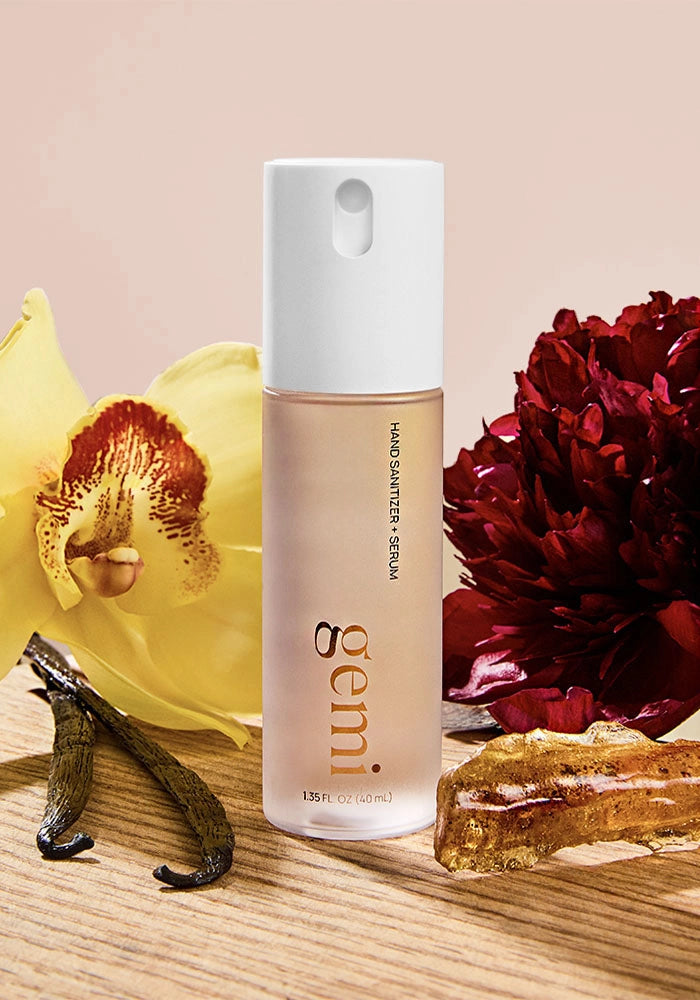 Hand sanitizer bottle labeled 'gemi' with peony and vanilla flowers on a beige background.